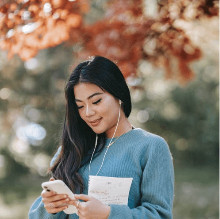 Image source: https://www.pexels.com/photo/young-cheerful-woman-listening-to-audio-book-using-smartphone-in-park-5965925/