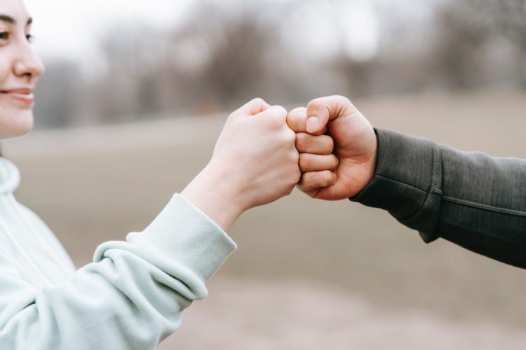 Photo by Andres  Ayrton: https://www.pexels.com/photo/man-and-happy-woman-greeting-each-other-with-fist-bump-6551298/