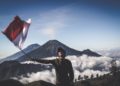 Photo by Dio Hasbi Saniskoro: https://www.pexels.com/photo/man-wearing-black-crew-neck-sweater-holding-white-and-red-flag-standing-near-mountain-under-blue-and-white-sky-1009949/