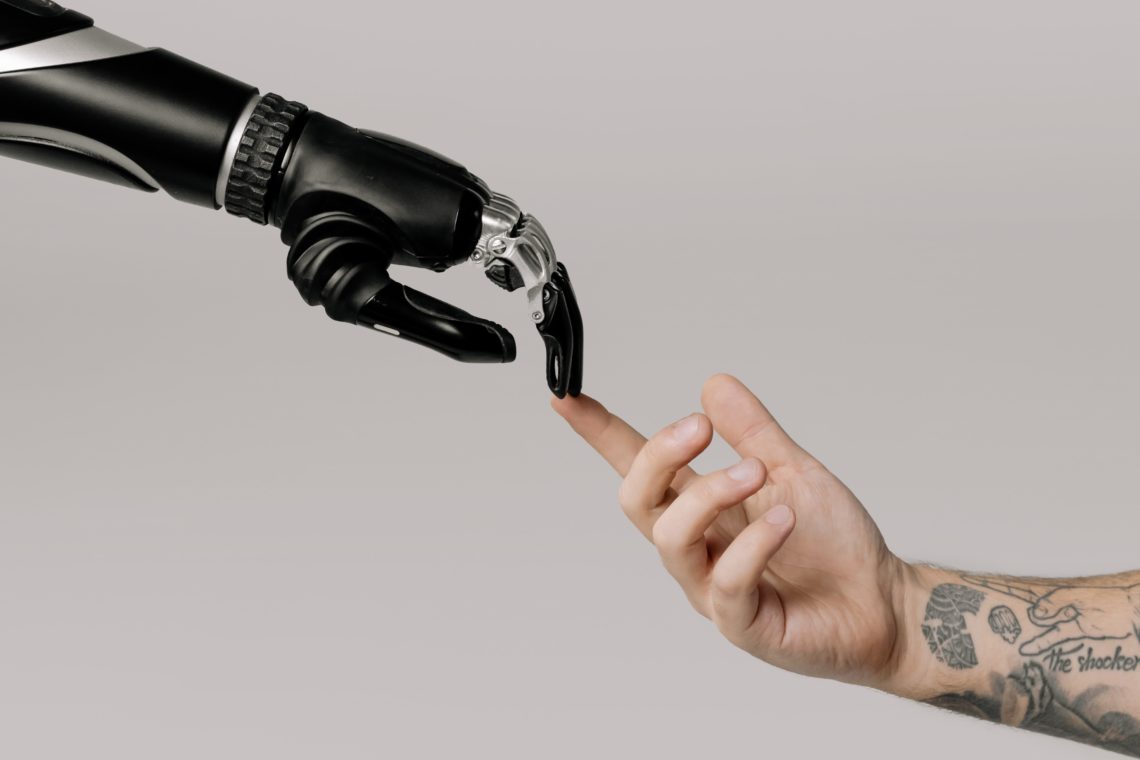 Photo by cottonbro studio: https://www.pexels.com/photo/bionic-hand-and-human-hand-finger-pointing-6153354/