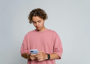 Photo by MART PRODUCTION: https://www.pexels.com/photo/man-in-pink-crew-neck-t-shirt-holding-blue-smartphone-9558694/
