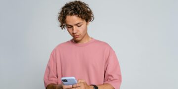 Photo by MART PRODUCTION: https://www.pexels.com/photo/man-in-pink-crew-neck-t-shirt-holding-blue-smartphone-9558694/